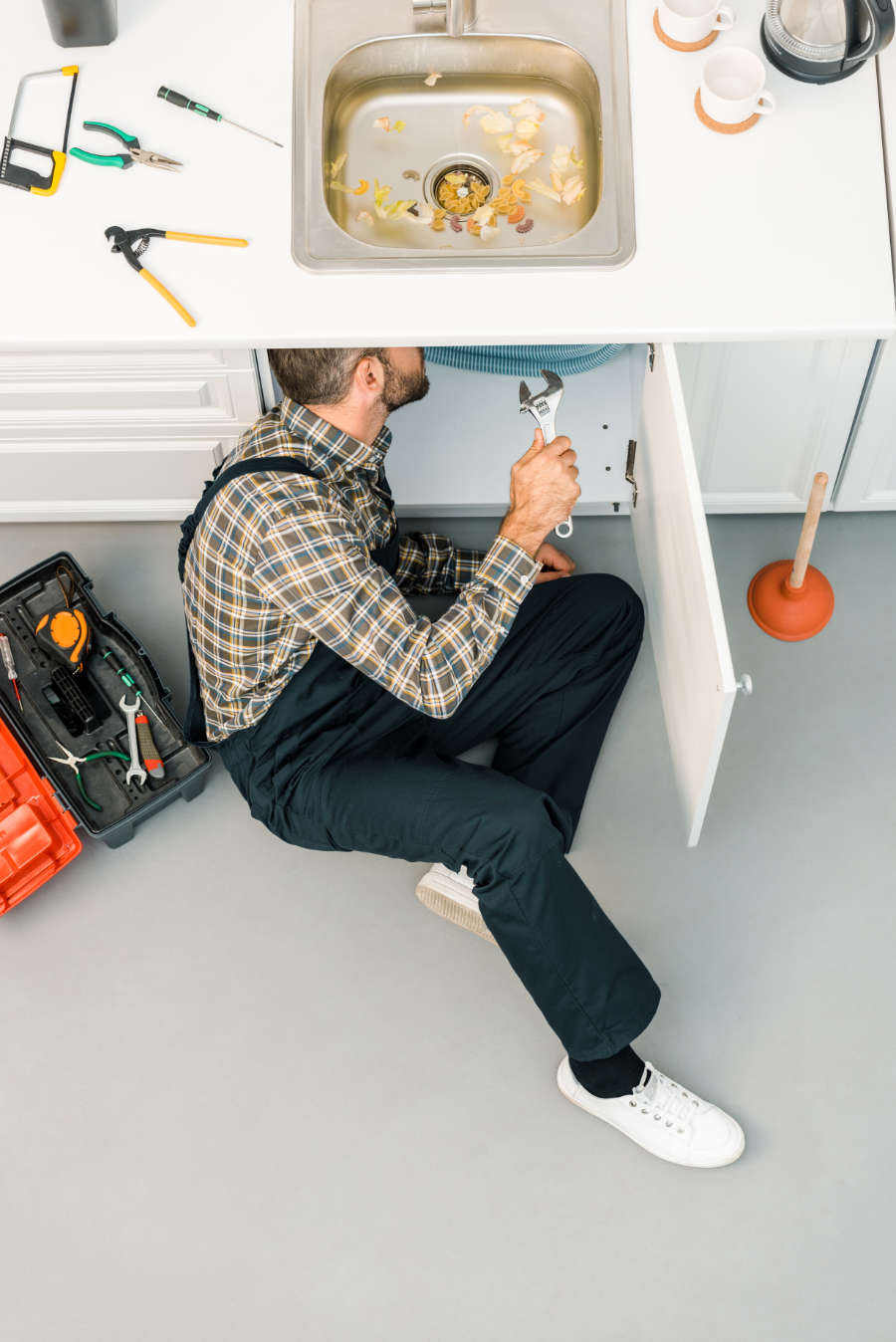 plumber repairing sink with adjustable wrench
